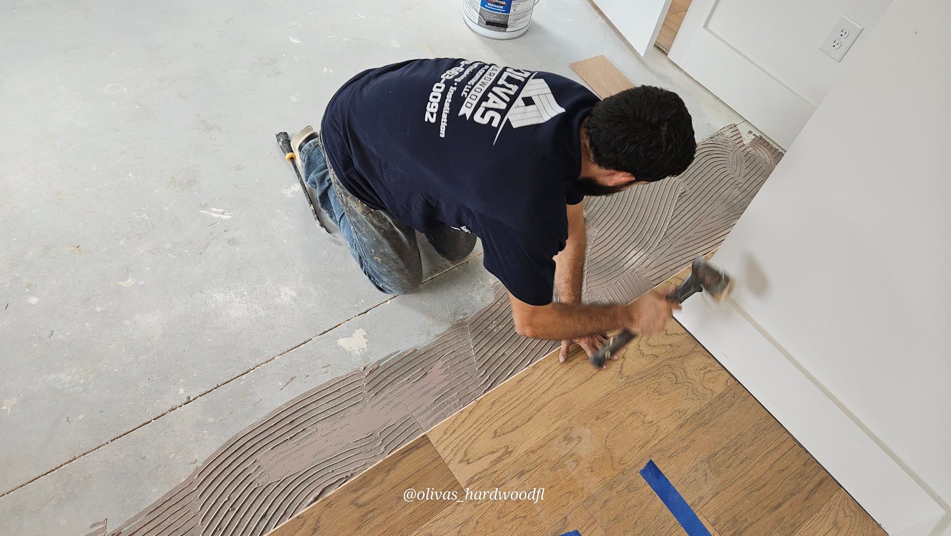 Olivas Hardwood Flooring crew member hammering hardwood plank into place during installation in Gwinnett County GA