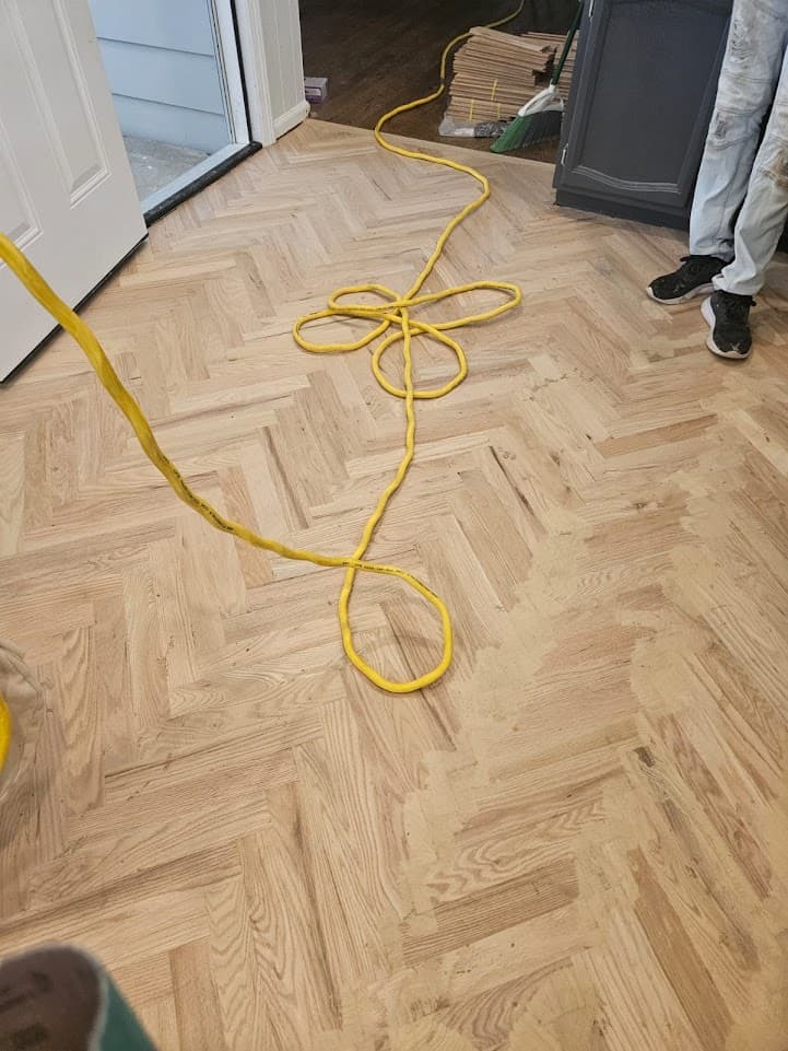 Herringbone hardwood floor installation in Gwinnett County GA — red oak parquet pattern in progress with pneumatic tools