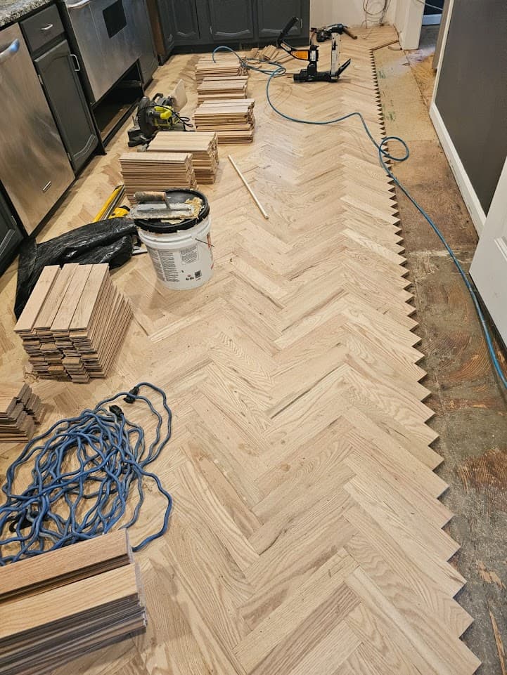 Herringbone hardwood floor installation in Atlanta GA — red oak parquet pattern laid in kitchen with tools