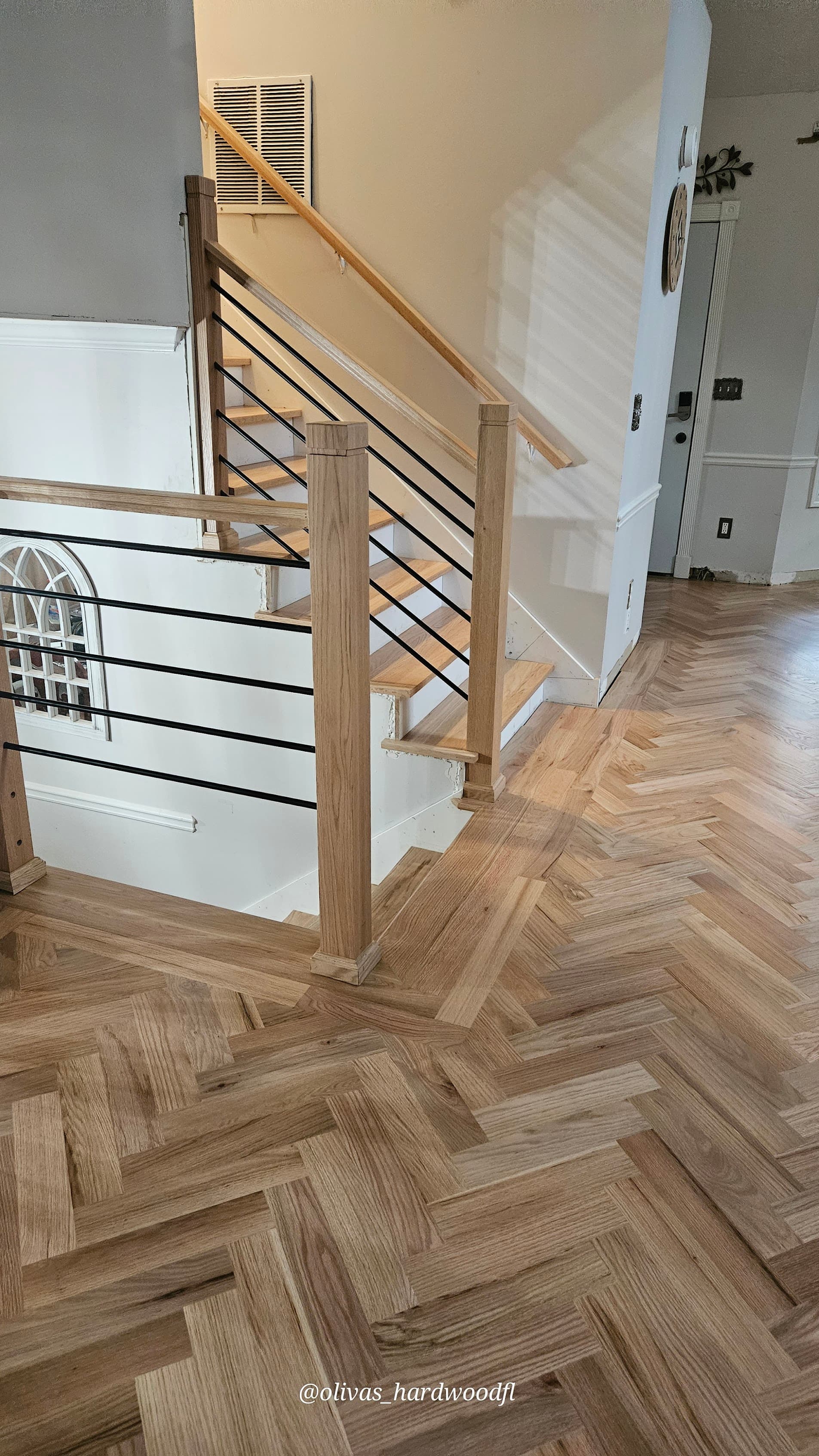 Hardwood installation in Duluth GA — natural oak staircase with modern horizontal rod balusters and herringbone floor