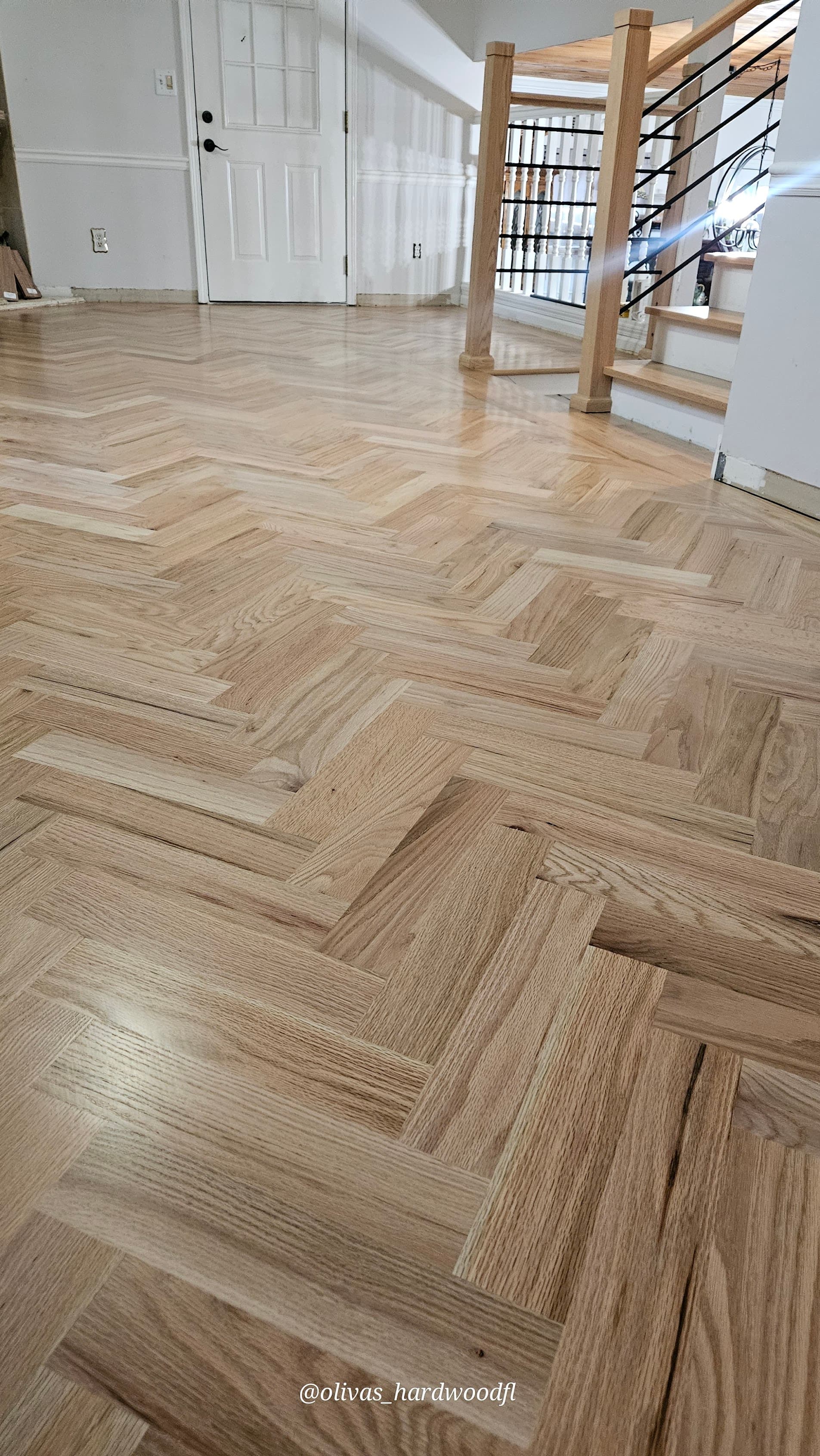 Herringbone hardwood floor installation in Gwinnett County GA — natural red oak foyer with staircase