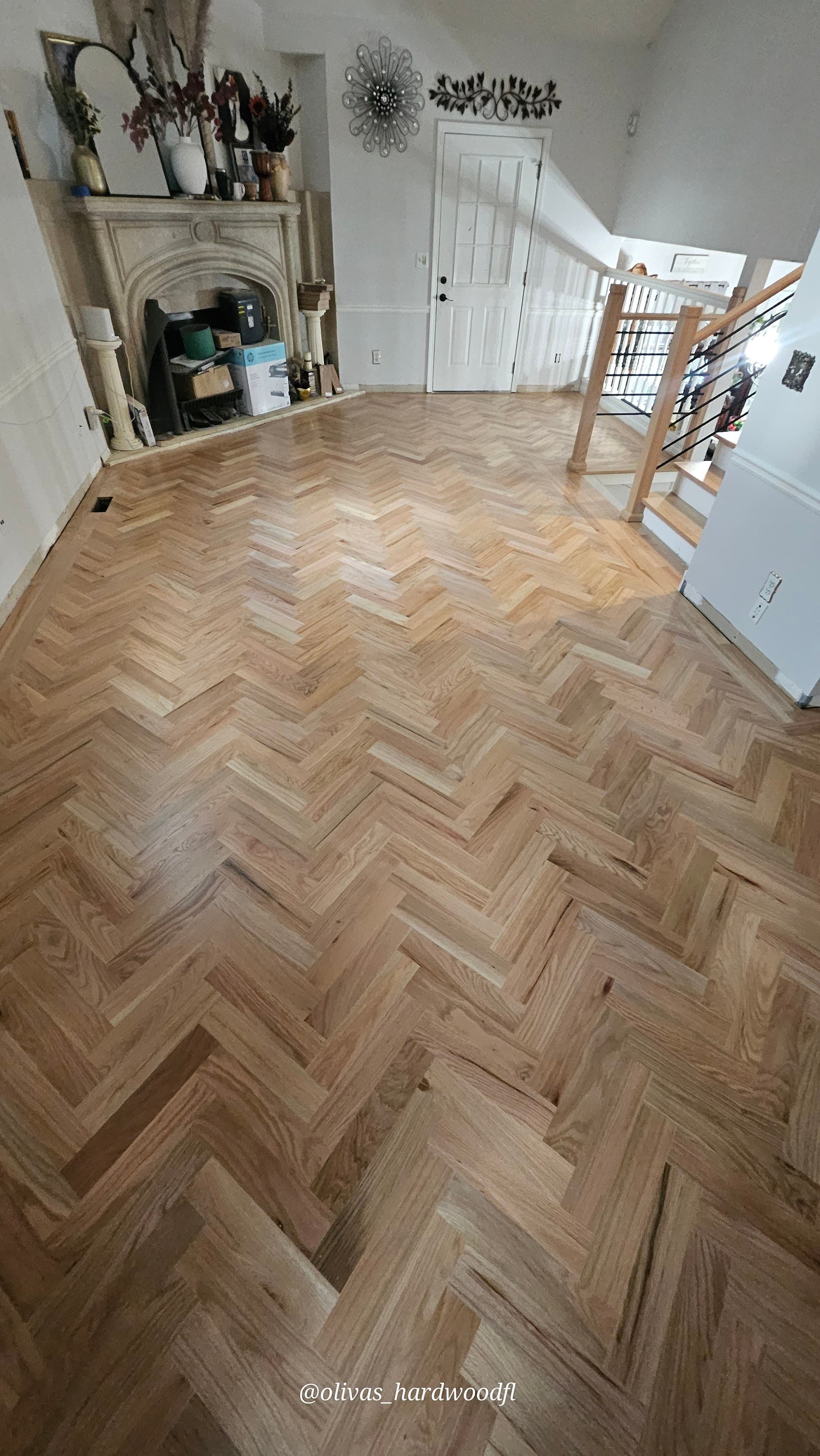 Herringbone hardwood floor installation in Roswell GA — natural oak living room with stone fireplace