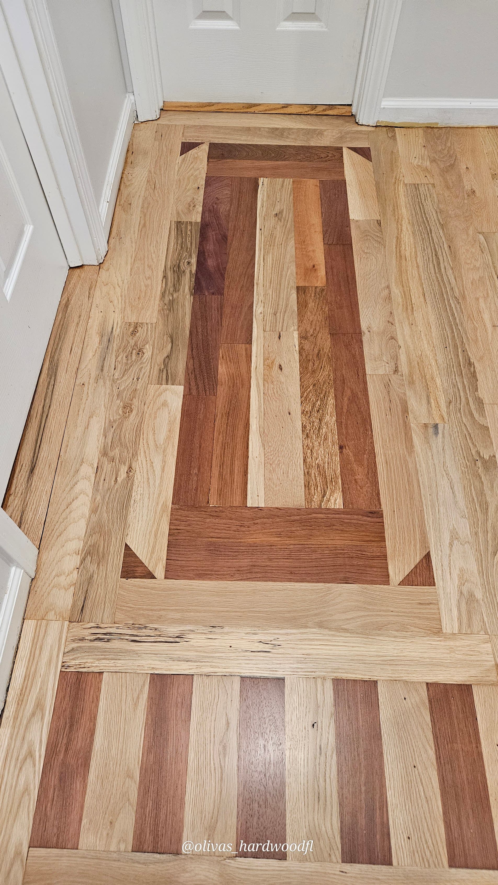 Custom parquet inlay hardwood floor installation in Lawrenceville GA — mixed species border pattern in hallway