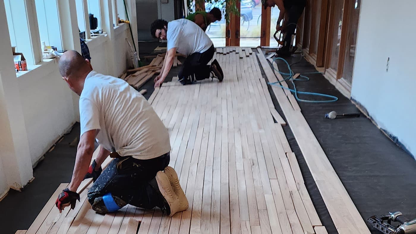 Hardwood floor installation in Atlanta GA — crew nailing down solid oak planks using nail-down method