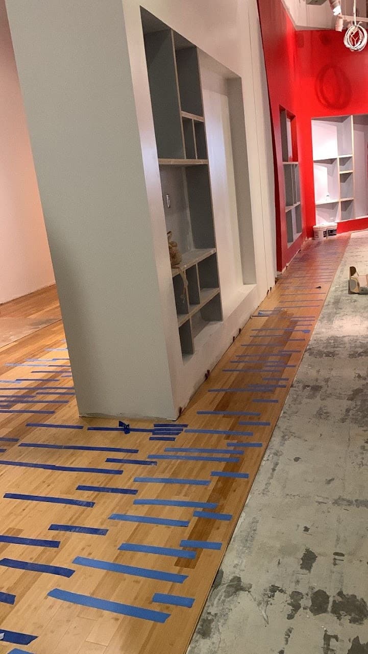 Commercial bamboo floor repair in Atlanta GA — board-by-board replacement marked in retail gallery space