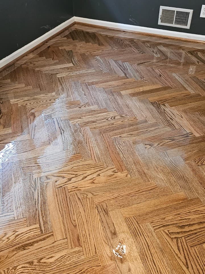 Herringbone hardwood floor refinishing in Marietta GA — medium honey stain on red oak parquet with dark walls