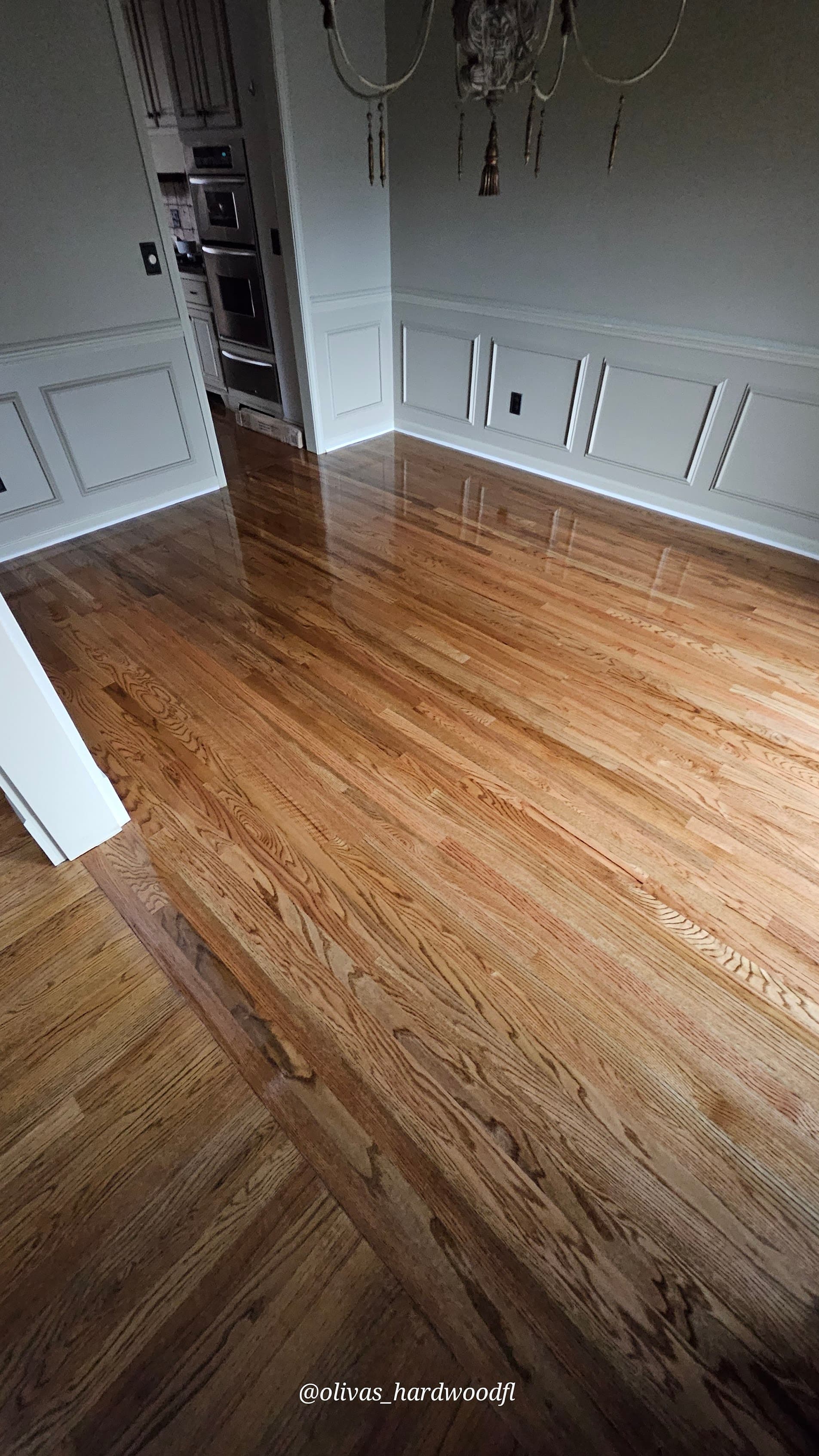 Hardwood floor refinishing in Johns Creek GA — gunstock stain red oak dining room with wainscoting and chandelier