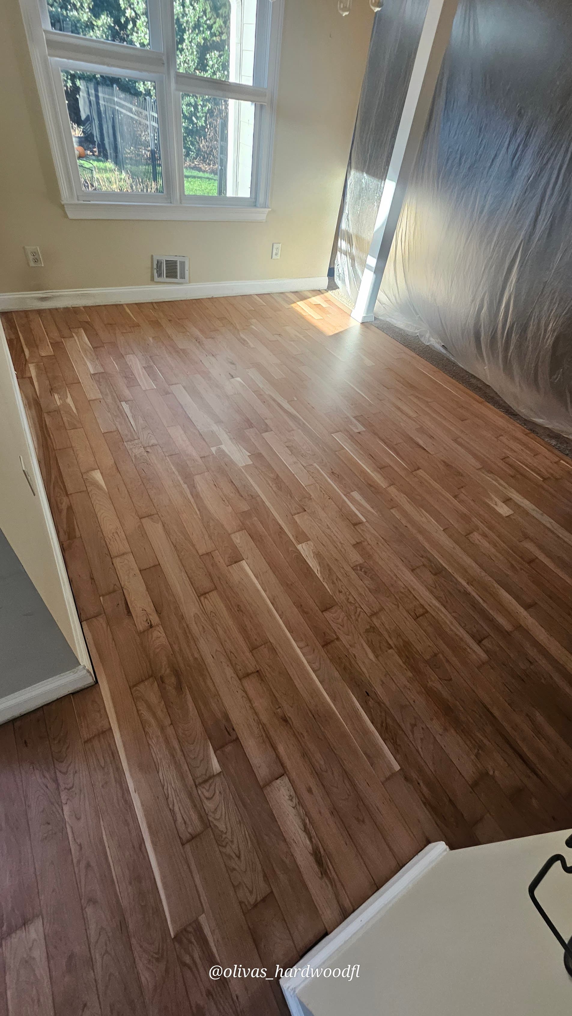 Hardwood floor refinishing in progress in Roswell GA — natural honey oak bedroom with protective sheeting
