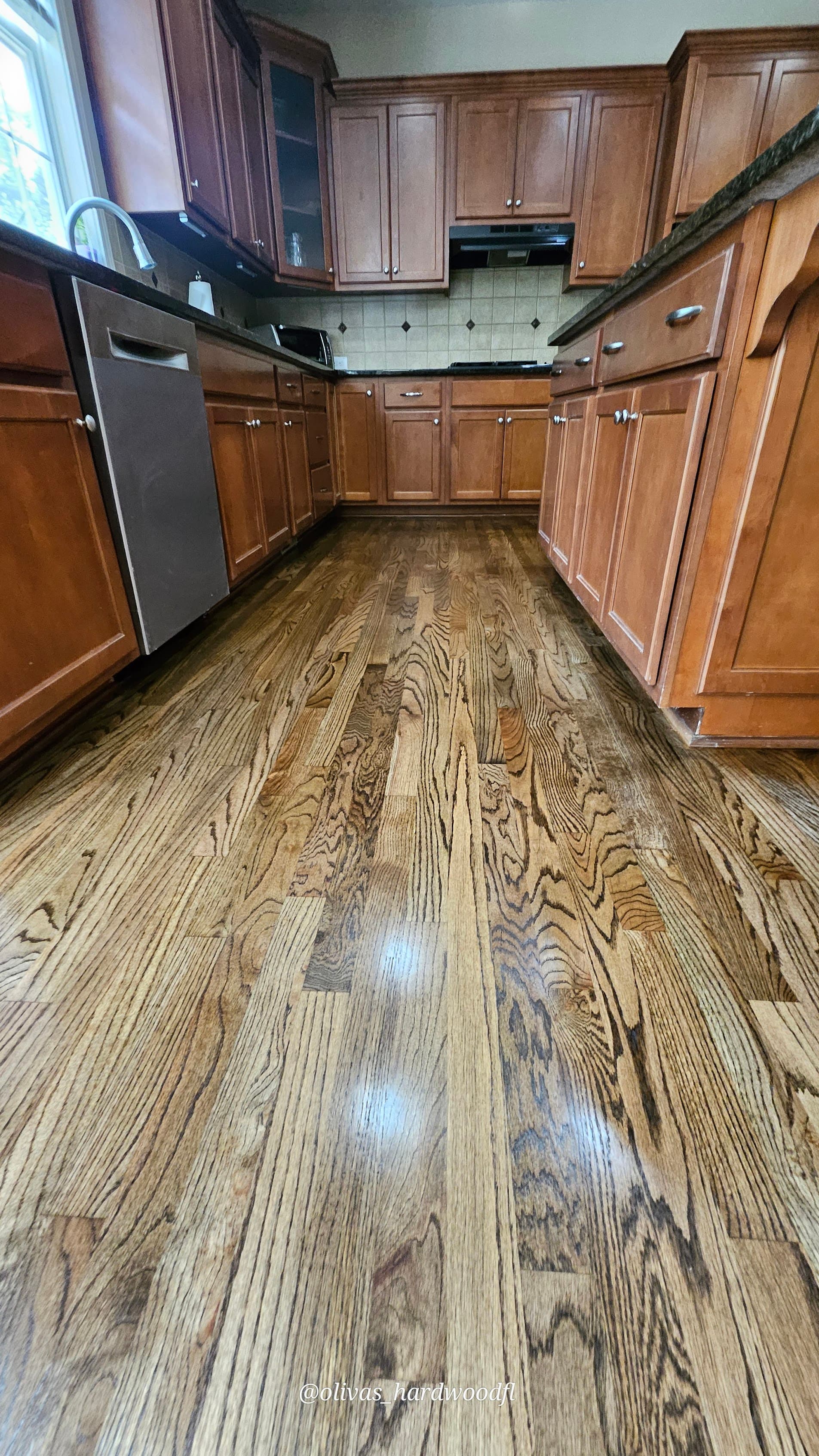 Hardwood floor refinishing in Atlanta GA — medium brown stain oak kitchen with dark cabinets and granite counters