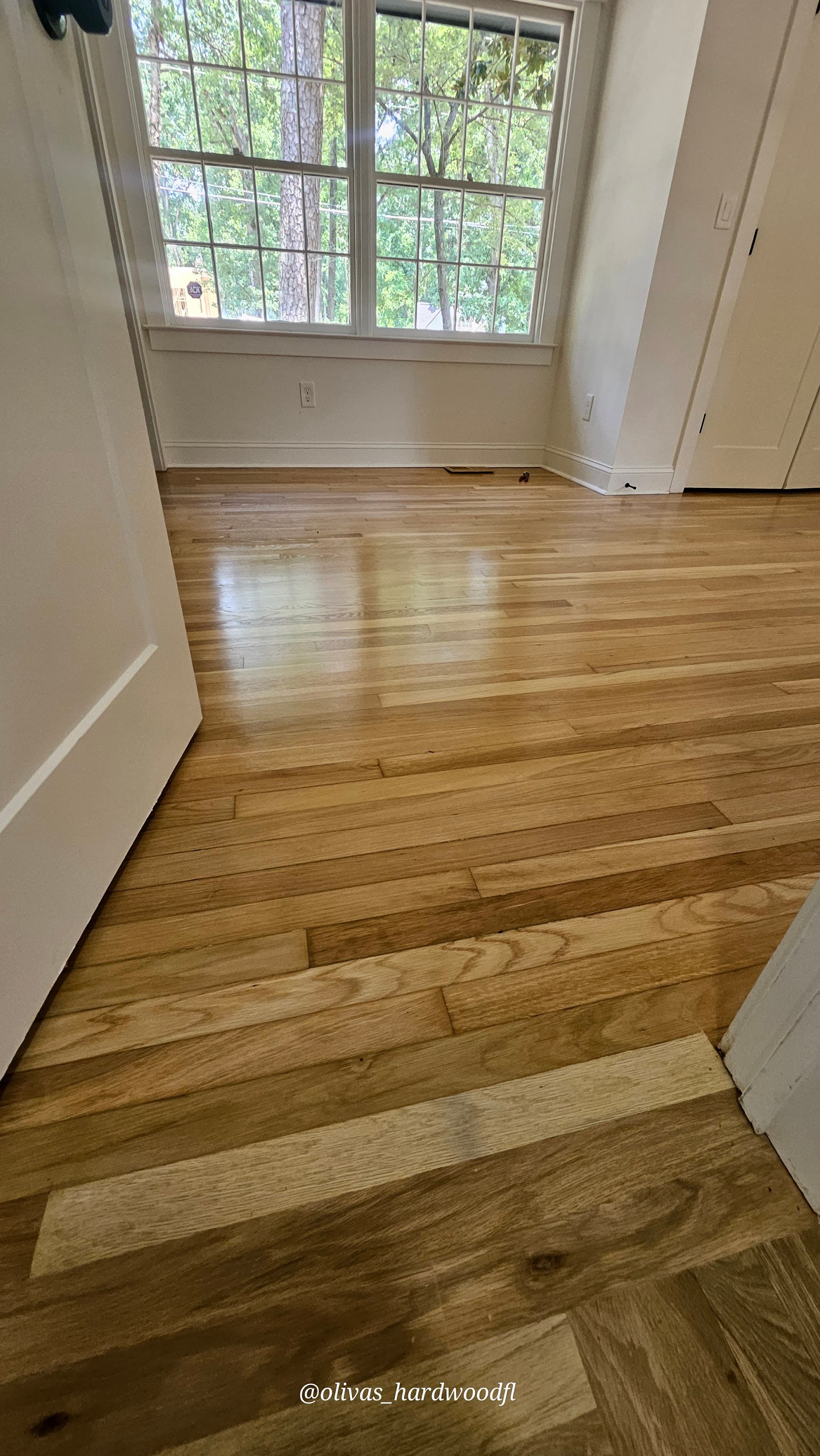 Hardwood floor refinishing in Gwinnett County GA — natural honey oak bedroom with large window