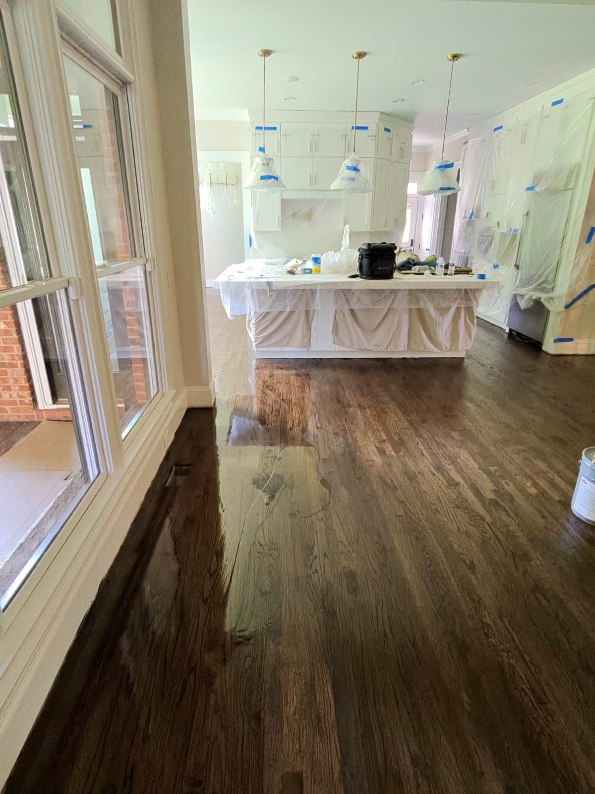 Hardwood floor refinishing in Lawrenceville GA — dark espresso stain oak kitchen with white cabinets protected during finishing