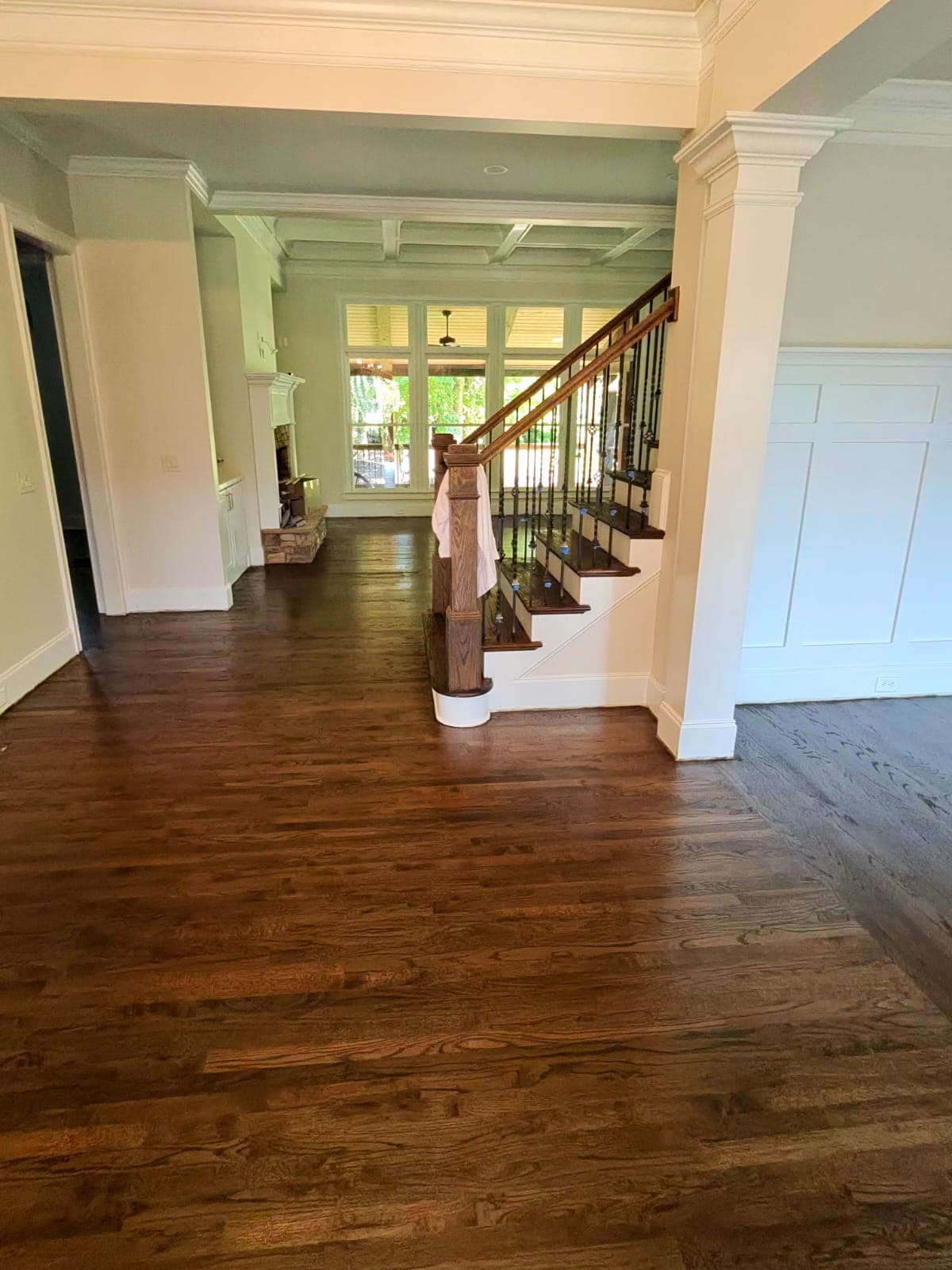 Hardwood floor refinishing in Johns Creek GA — medium brown stain oak foyer with staircase and iron balusters