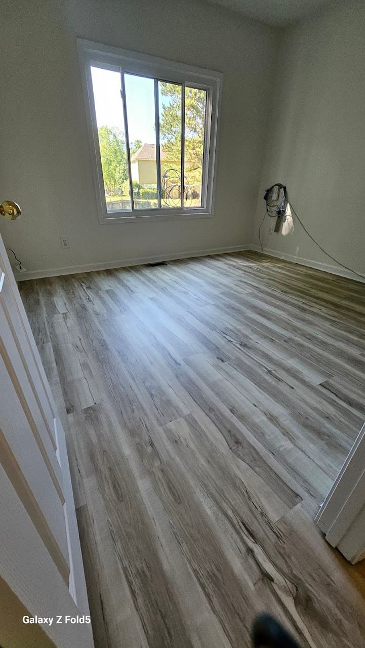 Luxury vinyl plank flooring in Lawrenceville GA — light gray-oak LVP in bedroom with large window
