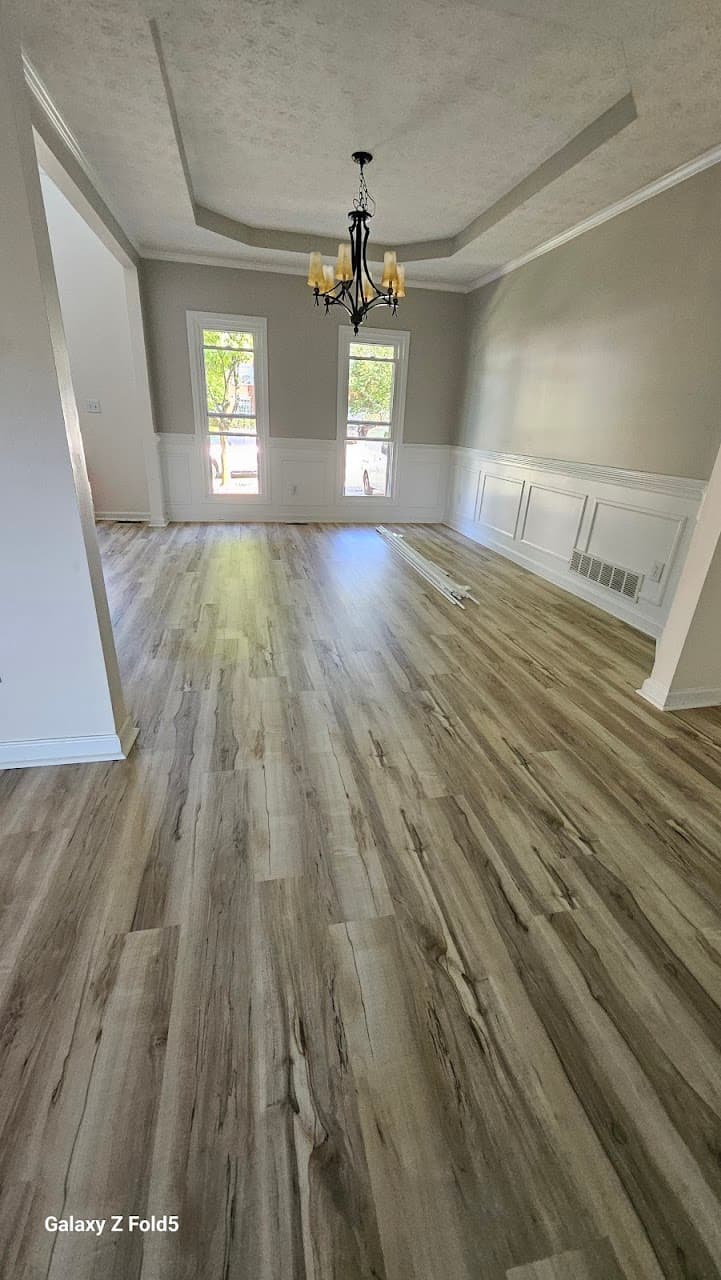 Luxury vinyl plank flooring in Alpharetta GA — light gray-oak LVP in dining room with tray ceiling and chandelier