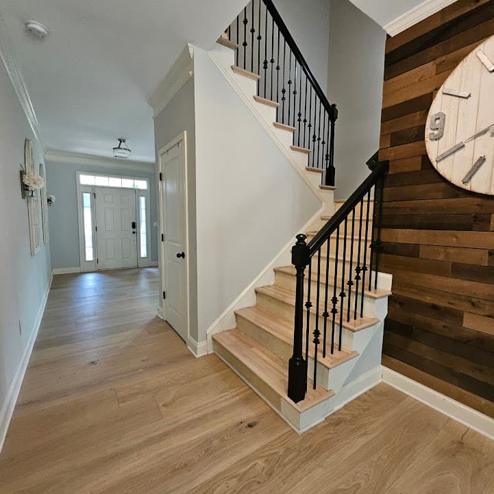 Staircase renovation in Suwanee GA — light oak treads with black iron balusters and shiplap accent wall