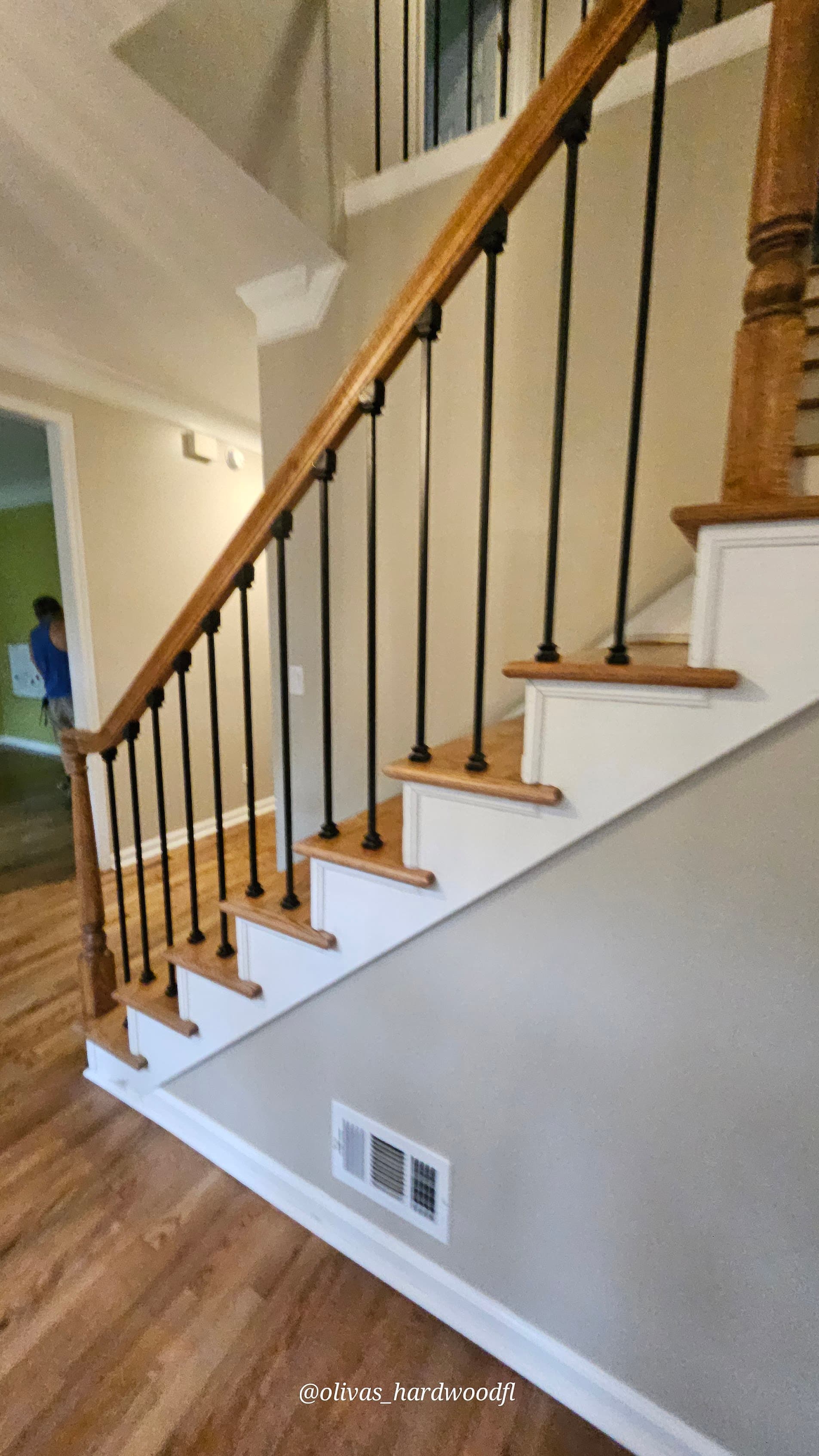 Staircase renovation in Lawrenceville GA — natural oak treads with iron balusters opening to hardwood foyer