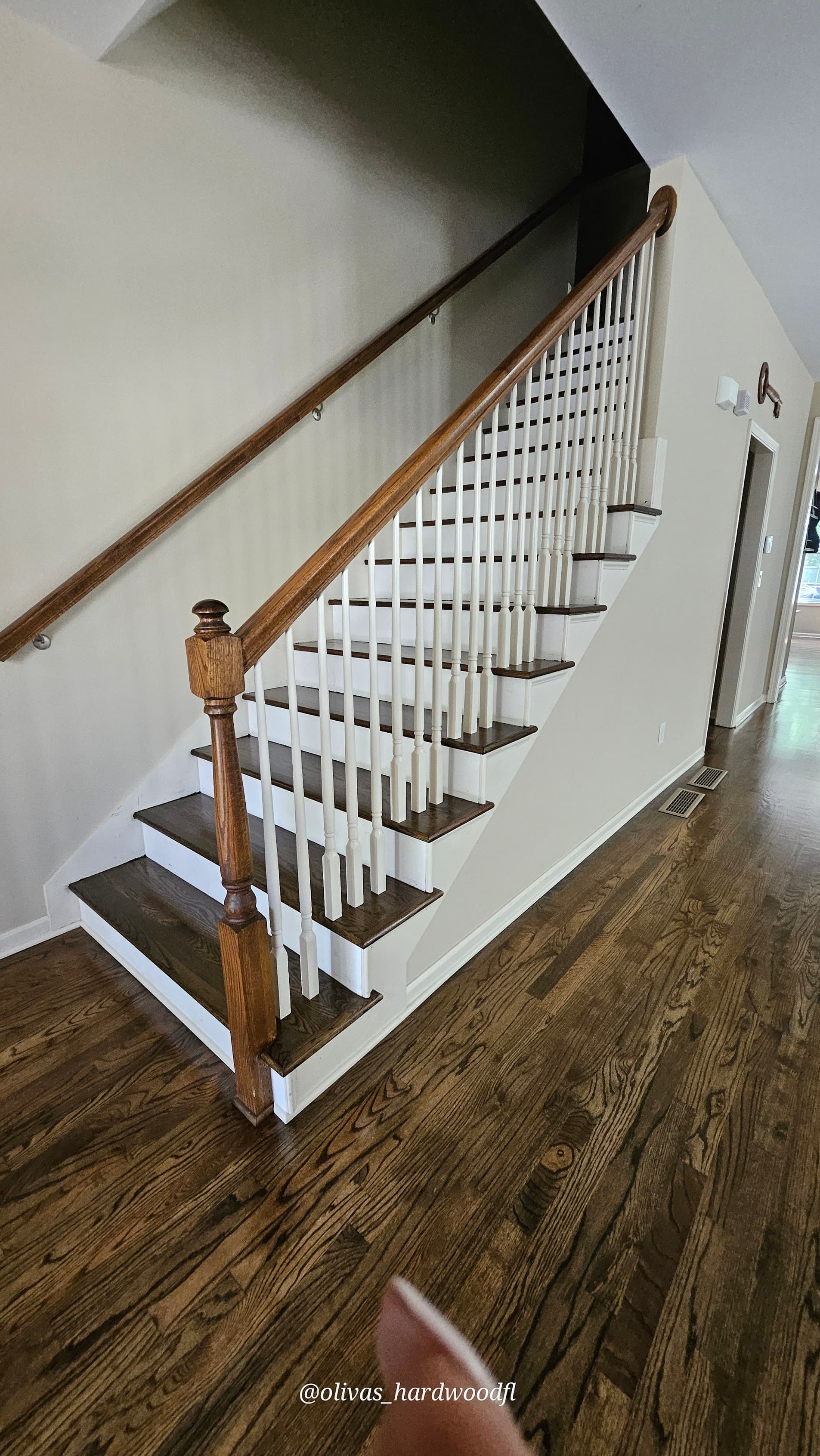 Staircase renovation in Duluth GA — dark oak treads with white painted spindles and matching hardwood floors
