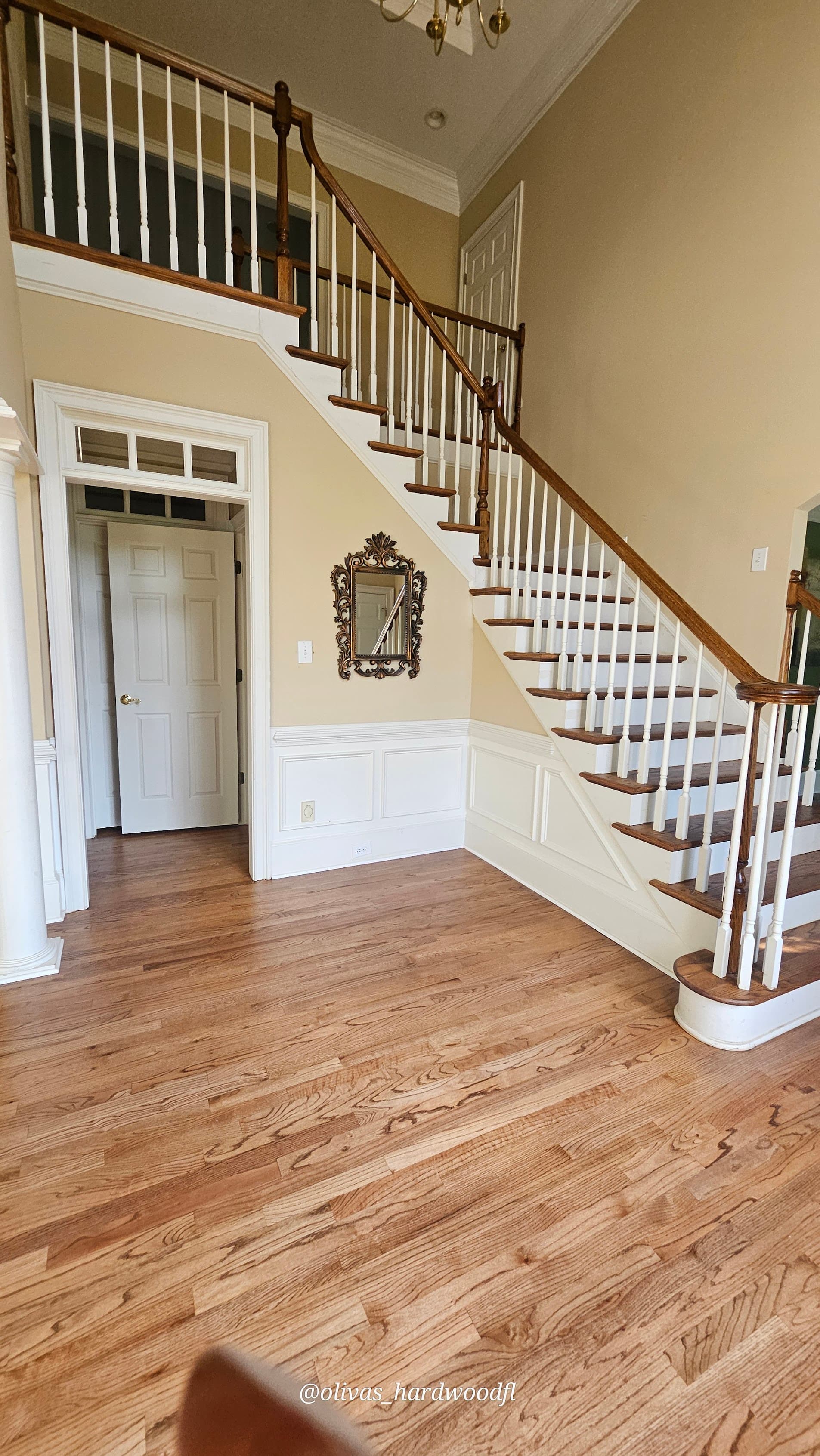 Grand staircase renovation in Roswell GA — natural oak treads with wainscoting and white spindles in foyer