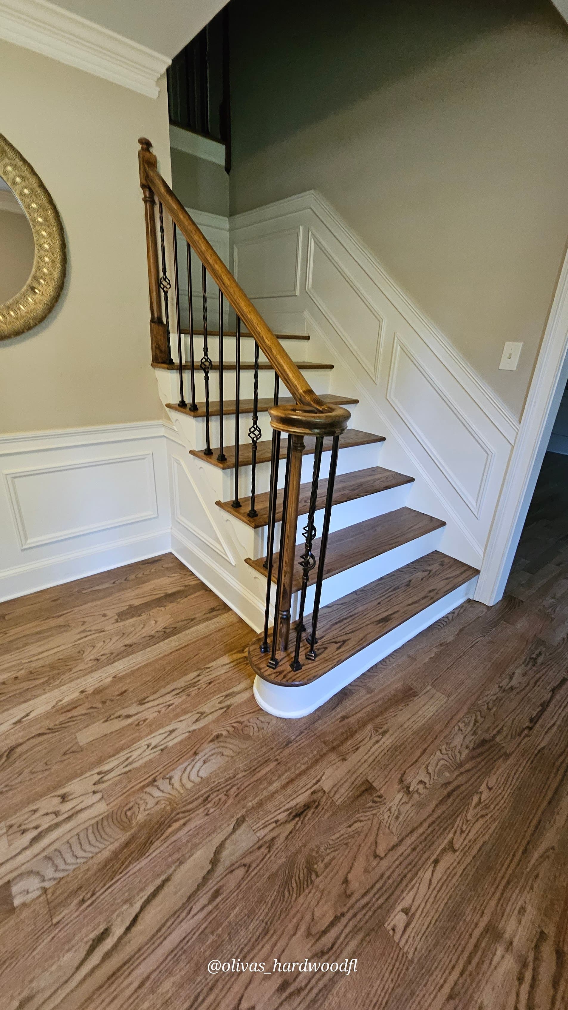 Staircase renovation in Marietta GA — medium brown oak treads with ornate iron balusters and hardwood foyer