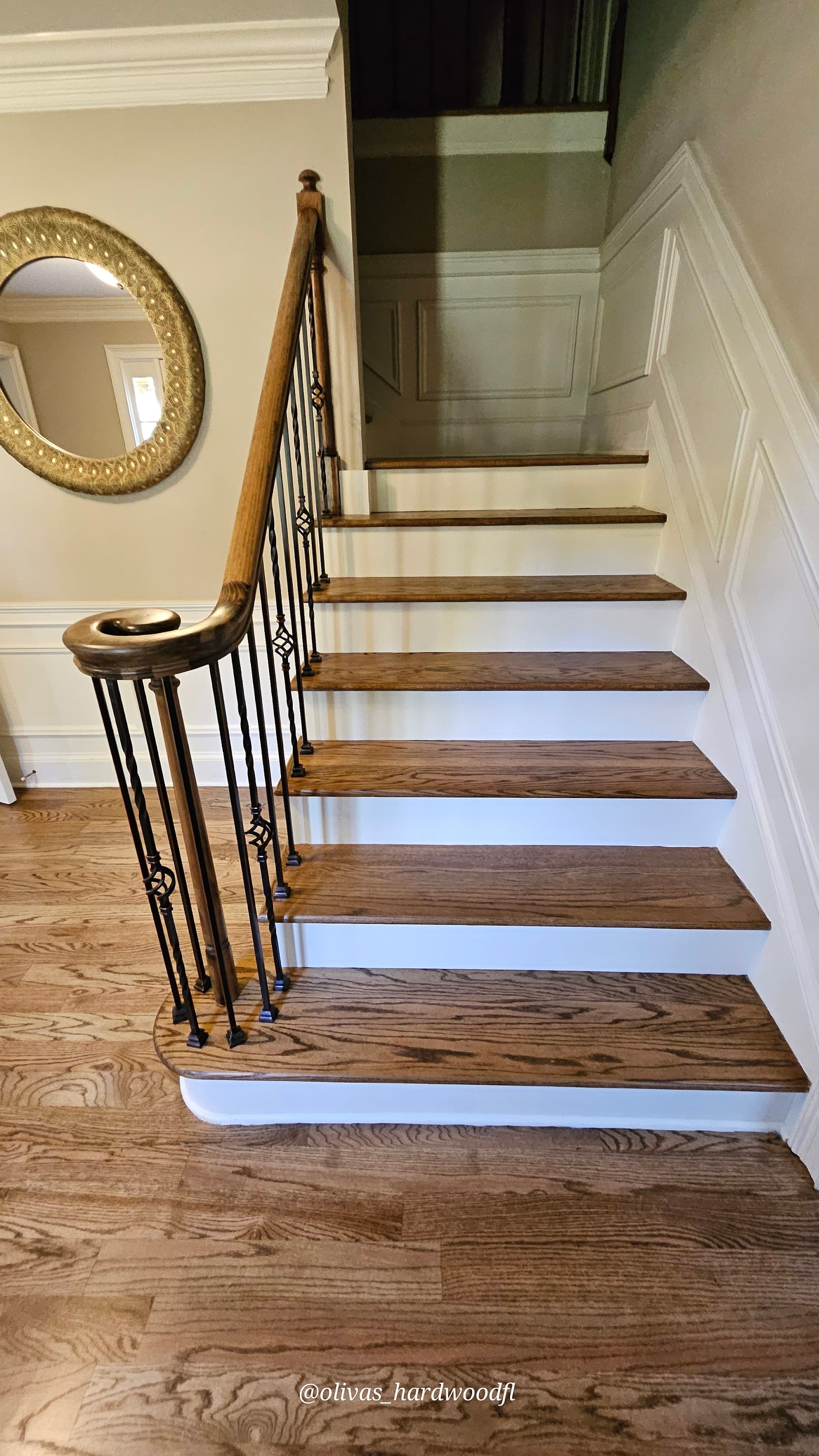 Staircase renovation in Lawrenceville GA — medium brown oak treads with ornate iron balusters and wainscoting