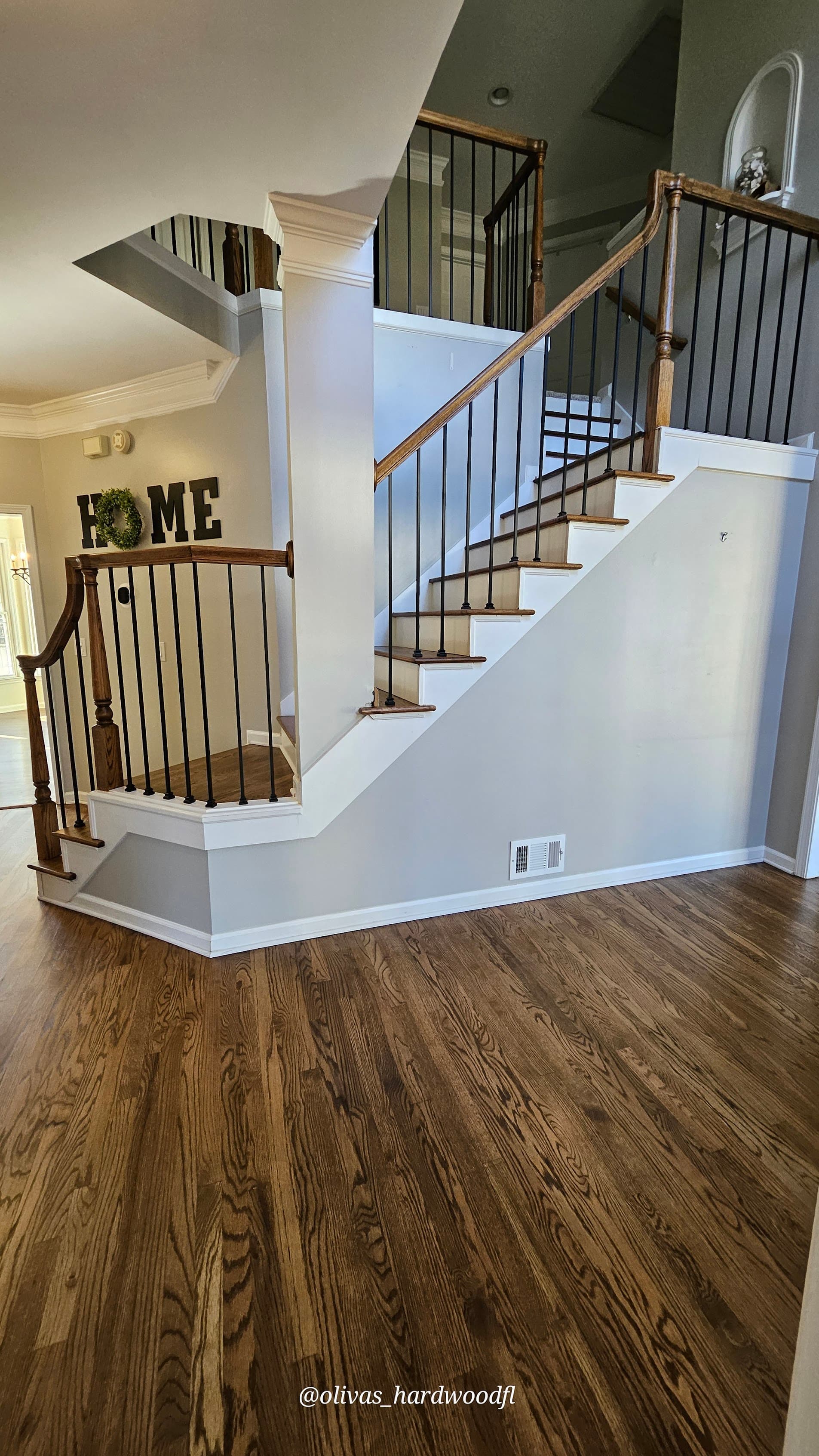 Open staircase renovation in Duluth GA — dark stain oak treads with iron balusters opening to hardwood foyer